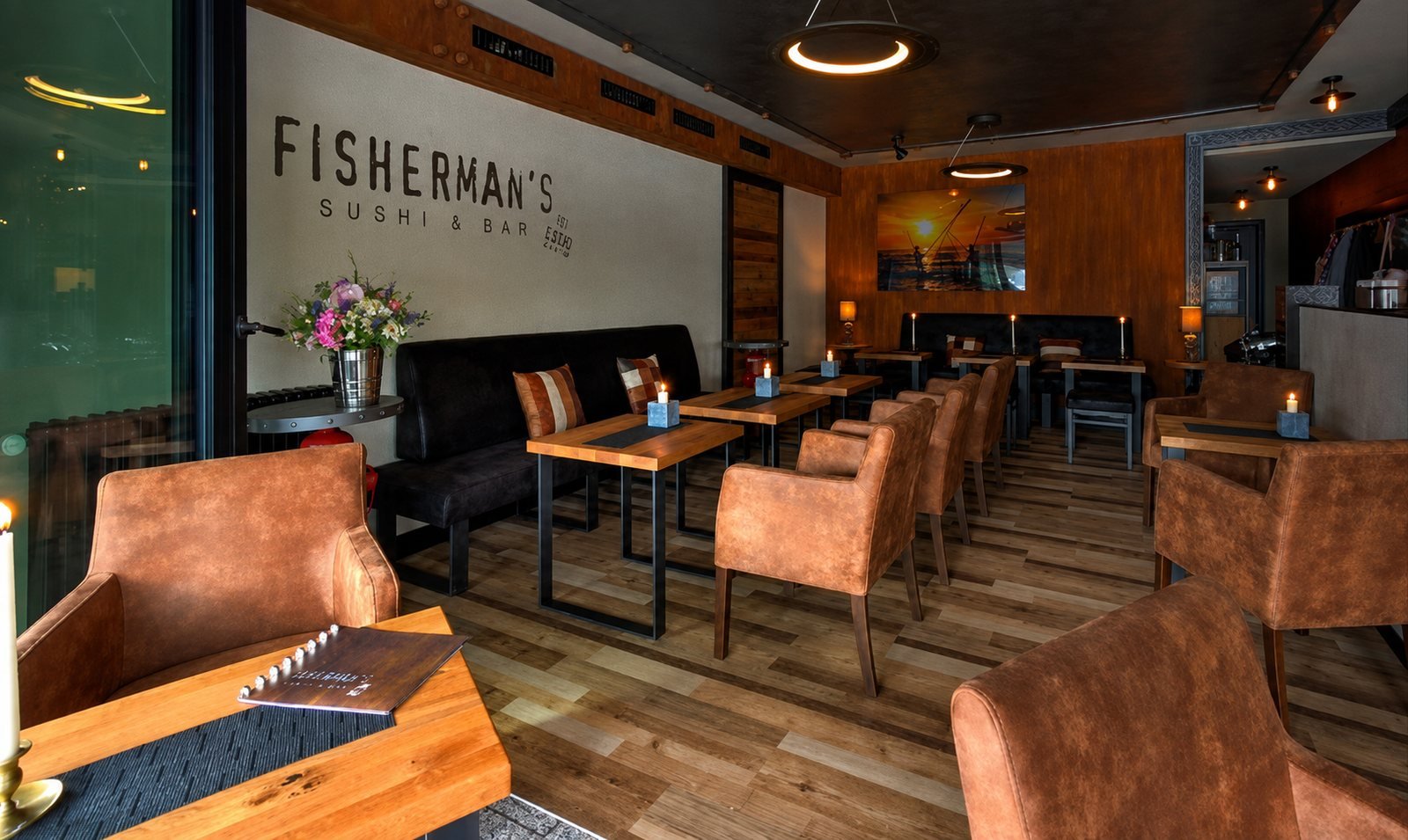 Gastraum mit Ledersesseln, Holztischen und dem Fisherman's Schriftzug an der Wand